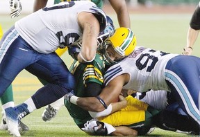 Toronto Argonauts' Cleyon Laing (90) and Ivan Brown (97) hit Edmonton Eskimos quarterback Mike Reilly (13) during first half action in Edmonton, Alta., on Saturday September 28, 2013. THE CANADIAN PRESS/Jason Franson.