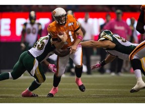 B.C. Lions' quarterback Buck Pierce, centre, gets away from Edmonton Eskimos' Rennie Curran, left, and Justin Capicciotti, right, and completes a pass to Andrew Harris for a touchdown during the first half of a CFL football game in Vancouver, B.C., on Friday October 25, 2013.
Photograph by: Darryl Dyck, The Canadian Press