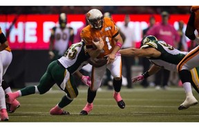 B.C. Lions' quarterback Buck Pierce, centre, gets away from Edmonton Eskimos' Rennie Curran, left, and Justin Capicciotti, right, and completes a pass to Andrew Harris for a touchdown during the first half of a CFL football game in Vancouver, B.C., on Friday October 25, 2013.
Photograph by: Darryl Dyck, The Canadian Press