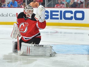 Goalie Cory Schneider of the New Jersey Devils looks back at the puck as it rings off of the post against the New York Rangers at the Prudential Center on October 19, 2013 in Newark, N.J.