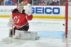 Goalie Cory Schneider of the New Jersey Devils looks back at the puck as it rings off of the post against the New York Rangers at the Prudential Center on October 19, 2013 in Newark, N.J.