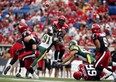 Edmonton Eskimos' Marcus Howard, left, tries to bring down Calgary Stampeders' quarterback Kevin Glenn, during first half CFL football action in Calgary on Sept. 2, 2013.