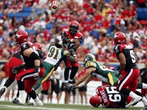 Edmonton Eskimos' Marcus Howard, left, tries to bring down Calgary Stampeders' quarterback Kevin Glenn, during first half CFL football action in Calgary on Sept. 2, 2013.
