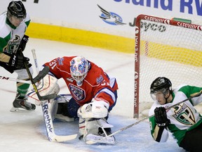 Prince Albert Raiders Shane Danyluk tries to get the puck past Regina Pats goalie Dawson MacAuley as Raiders Reid Gardiner trips backwards in Regina on Friday, Nov. 29, 2013.