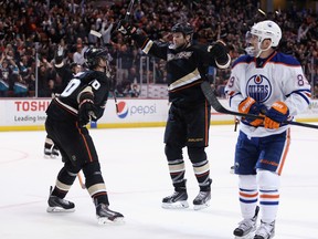 (L-R) Corey Perry #10 and Dustin Penner #17 of the Anaheim Ducks celebrate Penner's third period goal, as Sam Gagner #89 of the Edmonton Oilers looks on at Honda Center on December 15, 2013 in Anaheim, California. The Ducks defeated the Oilers 3-2.