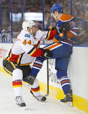 Ales Hemsky of the Edmonton Oilers gets checked into the board by Calgary Flames's Chris Butler during a National Hockey League game at Rexall Place on March 1, 2014.