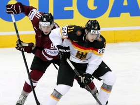 Leon Draisaitl , right, of Germany tries to protect the puck against Latvia's Ronalds Kenins during a world championship game at Minsk, Belarus, on May 11, 2014.