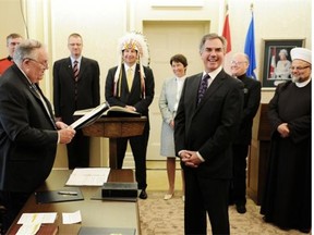 New Alberta Premier Jim Prentice is backed by provincial religious figures while being sworn in by Lt. Gov. Donald S. Ethell during the swearing in ceremony for him and new cabinet ministers at Government House in Edmonton on Monday Sept. 15, 2014.