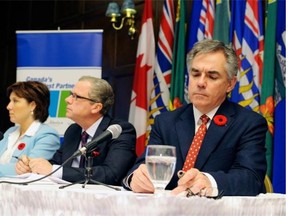 Alberta Premier Jim Prentice, right, takes notes during a press conference with B.C. Premier Christy Clark and Saskatchewan Premier Brad Wall in Regina on Thursday, Nov. 6, 2014.
