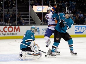 Alex Stalock #32 of the San Jose Sharks makes a save as Justin Braun #61 of the San Jose Sharks and David Perron #57 of the Edmonton Oilers fight for position in front of the net at SAP Center on December 9, 2014 in San Jose, California.