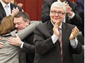 Alison Redford hugs Minister of Finance Doug Horner as Dave Hancock applauds the presentation of the budget in 2013.