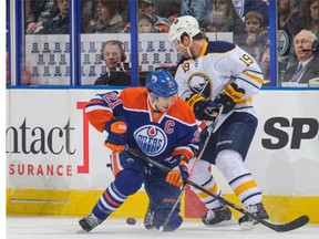 Andrew Ference, left, of the Edmonton Oilers battles for the puck against Cody Hodgson of the Buffalo Sabres during NHL action at Rexall Place on Thursday, March 20, 2014.