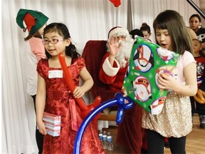 Anna Chen and Emily Klos leave the stage with gifts at the Sacred Heart Church of the First Peoples community Christmas party Saturday.