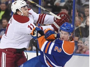 Arizona Coyotes forward Martin Hanzal, left, hits Edmonton Oilers defenceman Jeff Petry along the boards on Dec. 1, 2014, at Edmonton’s Rexall Place. The Coyotes won the game 5-2, handing the Oilers their 10th loss in a row.