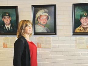Artist Susan Abma standing next to the Project Heroes portraits exhibit at the Prince of Wales Armouries in Edmonton, Nov. 7, 2014. Susan and two other artists are painting these portraits of the fallen soldiers.