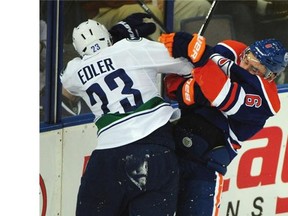 Canucks’ Alexander Edler and Jesse Joensuu, right, fight during Edmonton’s pre-season game against Vancouver at Rexall place on Thursday, Oct. 2, 2014.