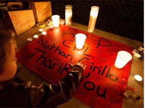 A child traces the name of Nathan Cirillo on a poster at a small candlelight vigil that was held Sunday in Corktown Park, the neighbourhood where Cirillo lived in Hamilton, Ont. The 24-year-old reservist was gunned down Wednesday as he stood ceremonial guard at the National War Memorial in Ottawa.