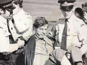 City police carry one of 70 apartheid protesters off the cricket field at Victoria Park where they had attempted to disrupt a match between the Edmonton team and a visiting English team.