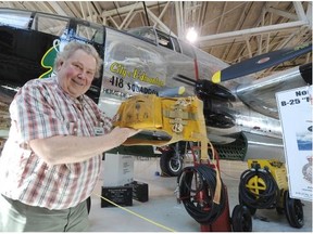 Cliff Adams holds a parachute that belonged to LAC Butch the dog, who was 418 Squadron’s mascot in the 1950s, in front of a B-25 Mitchell Bomber (in which the dog had many flights) at the Alberta Aviation Museum in Edmonton on Monday.