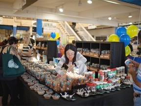 Connie Tam from Going Nuts restocks her table during the grand opening of Mother’s Market on 109th Street downtown.