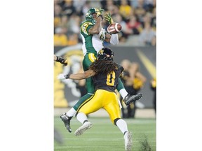 Edmonton Eskimos’ Adarius Bowman, left, leaps to make a catch over Hamilton Tiger-Cats’ Rico Murray during first half CFL action in Hamilton, Ont., on Saturday, September 20, 2014.