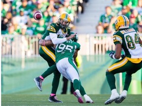 Edmonton Eskimos quarterback Mike Reilly gets hit by Saskatchewan Roughriders defensive end Ricky Foley just as he throws the ball during a Canadian Football League game at Mosaic Stadium in Regina on Oct. 19, 2014.