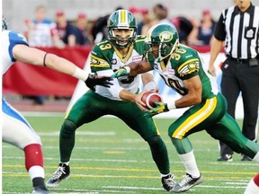 Edmonton Eskimos quarterback Mike Reilly hands the ball off to running back John White during a Canadian Football League game against the Alouettes at Molson Stadium in Montreal on Aug. 8, 2014.