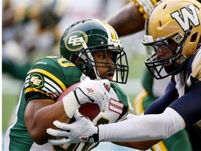 Edmonton Eskimos running back John White is tackled by Winnipeg Blue Bombers’ Jason Vega during a Canadian Football League game at Winnipeg’s Investors Group Field on July 17, 2014.