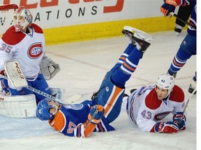 Edmonton Oilers Benoit Pouliot falls over Montreal Canadiens defenceman Mike Weaver (right) in front of Canadiens goalie Dustin Tokarski (left) during first period NHL game action in Edmonton on October 27, 2014.