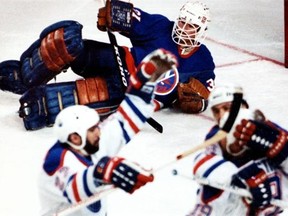 Edmonton Oilers defenceman Charlie Huddy, left, forward Willy Lindstrom, right, and an unidentified teammate celebrate a goal on New York Islanders goalie Billy Smith, background, during the Stanley Cup Finals in May 1984.