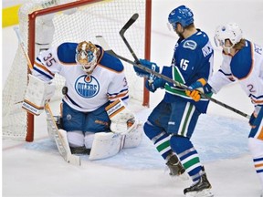 Edmonton Oilers defenceman Jeff Petry (2) ties to stop Vancouver Canucks centre Brad Richardson (15) from getting a shot on Edmonton Oilers goaltender Viktor Fasth (35) during the first period of NHL action in Vancouver, B.C., Saturday, Oct. 11, 2014.