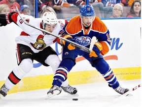Edmonton Oilers defenceman Justin Schultz battles for the pick with Ottawa Senators forward Mika Zibanejad during a National Hockey League game at Rexall Place on March 4, 2014.