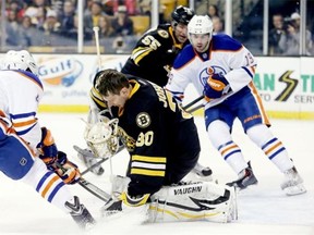 Edmonton Oilers defenceman Justin Schultz (19) watches as Boston Bruins goalie Chad Johnson loses his helmet while making a save on a shot by left-winger Taylor Hall, left, during Saturday’s National Hockey League game at the TD Garden.