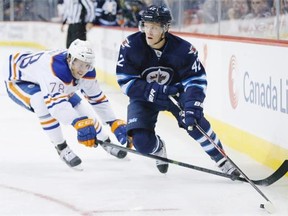 Edmonton Oilers defenceman Martin Gernat, left, attempts to knock the puck off Winnipeg Jets forward Nikolaj Ehlers during second period NHL pre-season action in Winnipeg on Wednesday, Sept. 24, 2014.