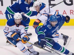 Edmonton Oilers forwards Ryan Nugent-Hopkins and Taylor Hall (4) fight for control of the puck with Vancouver Canucks defenceman Dan Hamhuis (2) and teammate Brad Richardson during a National Hockey League game at Vancouver on Oct. 11, 2014.