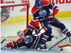 Edmonton Oilers goalie Ben Scrivens is knocked over by defenceman Jeff Petry while Vancouver Canucks forward Nick Bonino bangs at the puck during Wednesday’s National Hockey League game at Rexall Place.