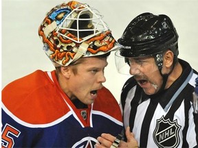 Edmonton Oilers goalie Viktor Fasth, left, gets into a serious discussion with linesmen Andy McElman while playing the New Jersey Devils during NHL action at Rexall Place in Edmonton on Friday, Nov. 22, 2014.