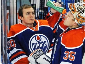 Edmonton Oilers goalie Viktor Fasth (35) squirts water in his face as goalie Ben Scrivens (30), who was taken out in the second period, looks on against the Chicago Black Hawks during NHL action at Rexall Place in Edmonton, November 23, 2014. The Oilers lost 7-1.