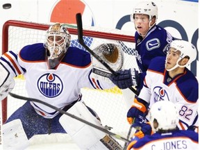 Edmonton Oilers netminding prospect Laurent Brossoit eyes a flying puck along with defenseman Jordan Oesterle, No. 82, and centre Connor Jones, No. 66,  during the first period at the YoungStars Tournament in Penticton, B.C., on Friday, Sept. 12, 2014. In on the play for Vancouver Canucks is Hunter Shinkaruk.