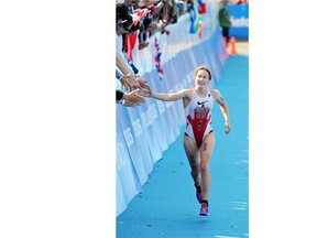 Edmonton’s Paula Findlay high-fives fans before crossing the finish line in the elite women’s ITU Grand Final race at Hawreluk Park on Aug. 30, 2014.