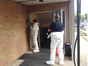 Edmonton police put on plastic protective suits before entering an apartment on the second-floor of a walk-up apartment building near Whyte Avenue Tuesday morning. A man was found in the suite on Monday suffering from a gun shot wound to the head.