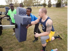 Edmonton Wildcats defensive end Keaton Hoddinott gives some tips on how to work the blocking sled to Zack Mohamed, 12, during the Prairie Football Conference team’s flag football camp for Big Brothers/Big Sisters on Sept. 18, 2014.
