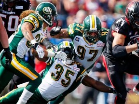 From left, defensive half ack Aaron Grymes, middle linebacker Rennie Curran and defensive tackle Eddie Steele combine efforts to tackle Calgary Stampeders running back Jon Cornish in a Canadian Football League game at McMahon Stadium in Calgary on Sept. 1, 2014.