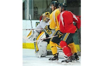 From left, goalie Luke Siemens, T.J. Foster and Stephane Legault watch a play in front of the net during a University of Alberta Golden Bears hockey practice at Clare Drake Arena on Nov. 18, 2014.