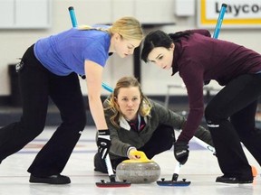 Jen Gates, left, and Taylor McDonald sweep skip Chelsea Carey’s rock in the women’s final at the HDF Insurance Shoot-Out bonspiel at the Saville Community Sports Centre on Sunday.