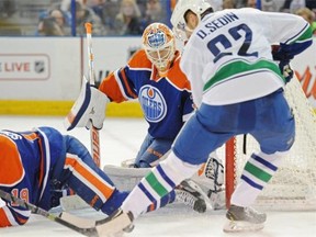 Goalie Ben Scrivens (30)of the Edmonton Oilers, eyes the puck at the feet of Daniel Sedin of the Vancouver Canucks at Rexall Place in Edmonton.