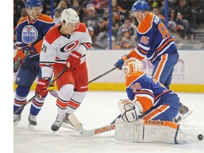 Goalie Ben Scrivens (30) of the Edmonton Oilers, is unable to stop a point shot as Alexander Semin of the Carolina Hurricanes jumps to get out of the way at Rexall Place in Edmonton.