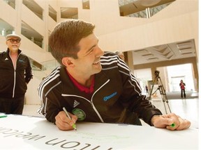 Mayor Don Iveson signs a banner on Friday, as Coun. Scott McKeen watches, encouraging people to attend the FIFA U-20 Women’s World Cup Canada 2014 quarter final at Commonwealth Stadium on Saturday.