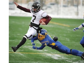 Henry Wise Wood quarterback Peter Zajdel tries to elude Colin Mitchell of the Bev Facey Falcons during the Alberta high school football Tier I semifinal at Clarke Field on Nov 15, 2014.