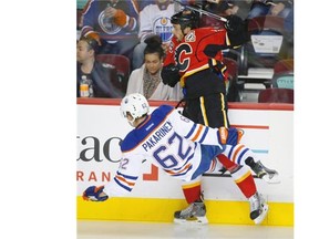 Iiro Pakarinen of the Edmonton Oilers checks Deryk Engelland of the Calgary Flames during NHL pre-season action in Calgary on Sept. 21, 2014.